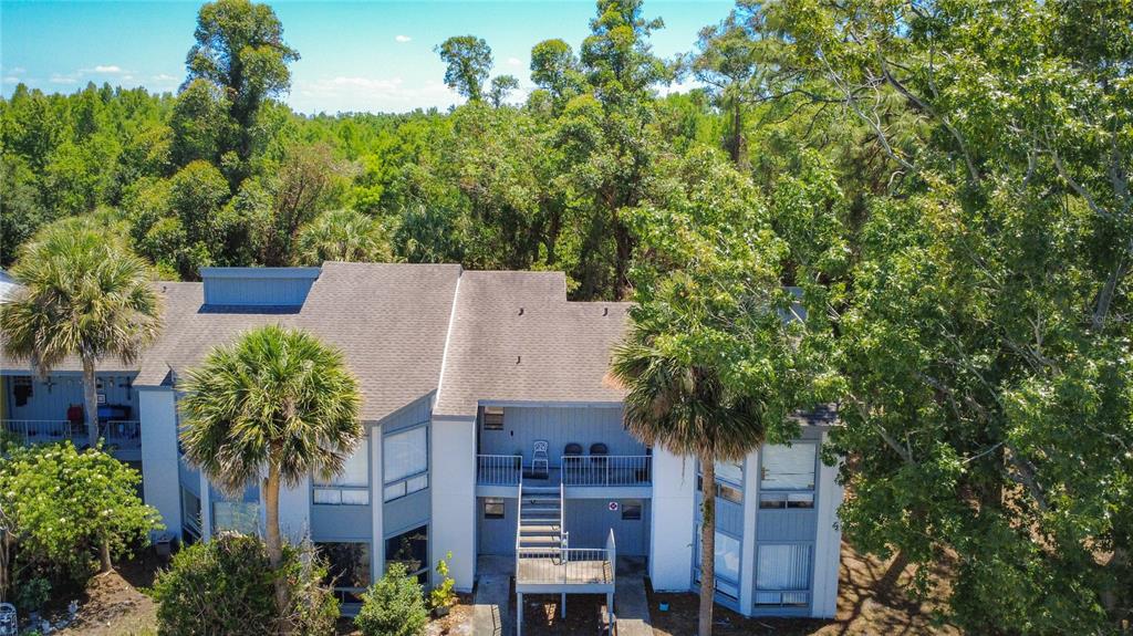 An aerial view of a two-story blue apartment building surrounded by dense green trees — 2636 LEMON TREE LANE, ORLANDO, FL