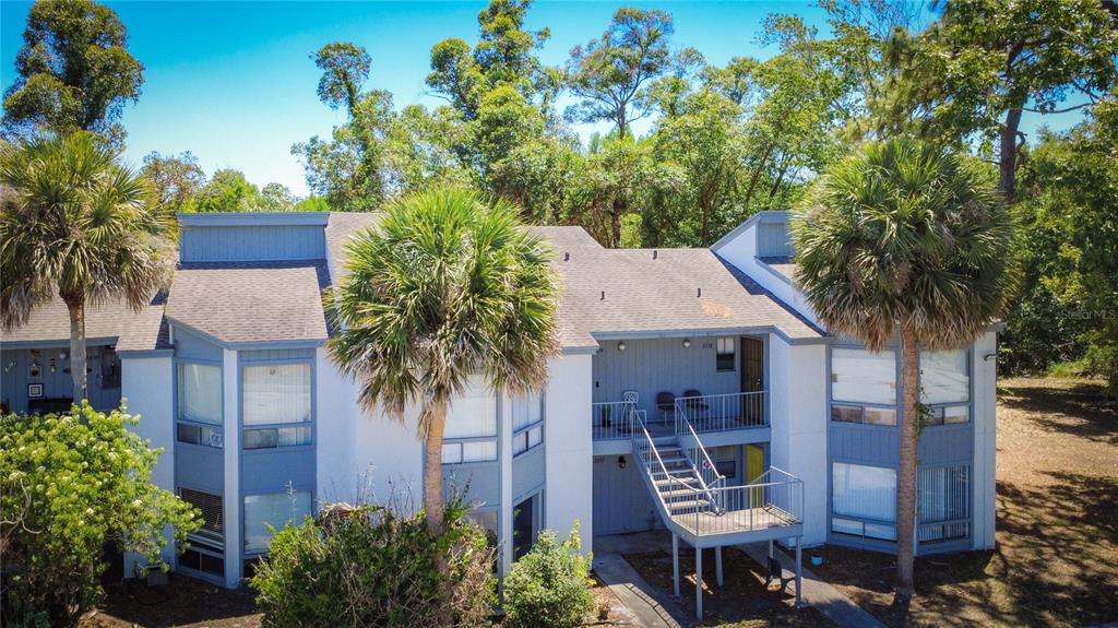 An exterior view of a two-story apartment building with a metal staircase and palm trees — 2636 LEMON TREE LANE, ORLANDO, FL