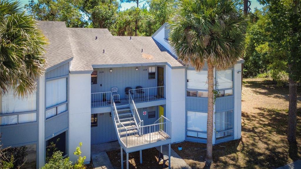 An exterior view of a two-story apartment building with blue siding and an outdoor staircase — 2636 LEMON TREE LANE, ORLANDO, FL