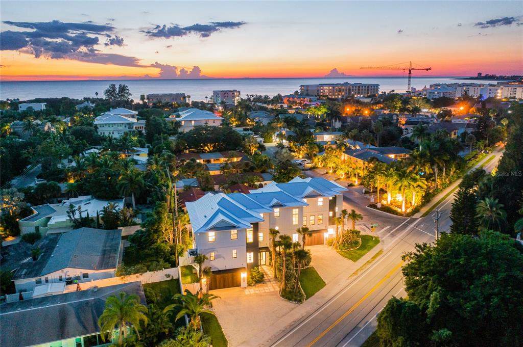 An aerial view shows a modern white house with a metal roof at sunset — 6910 MIDNIGHT PASS ROAD UNIT A, SARASOTA, FL