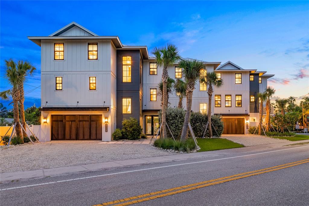 A three-story modern residential building with white vertical siding, dark accents, and two garages — 6910 MIDNIGHT PASS ROAD UNIT A, SARASOTA, FL
