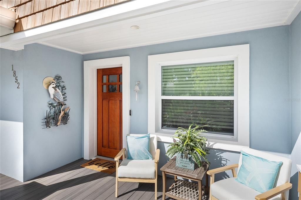 A covered front porch features a wooden door, two chairs, a small table, and decor — 1852 S FLAGLER AVENUE, FLAGLER BEACH, FL