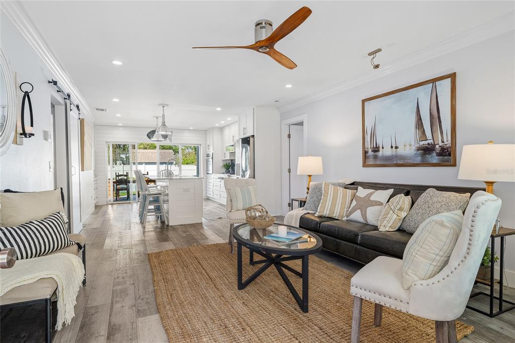 A bright living room with wood-look flooring flows into an open kitchen with white cabinetry — 1852 S FLAGLER AVENUE, FLAGLER BEACH, FL