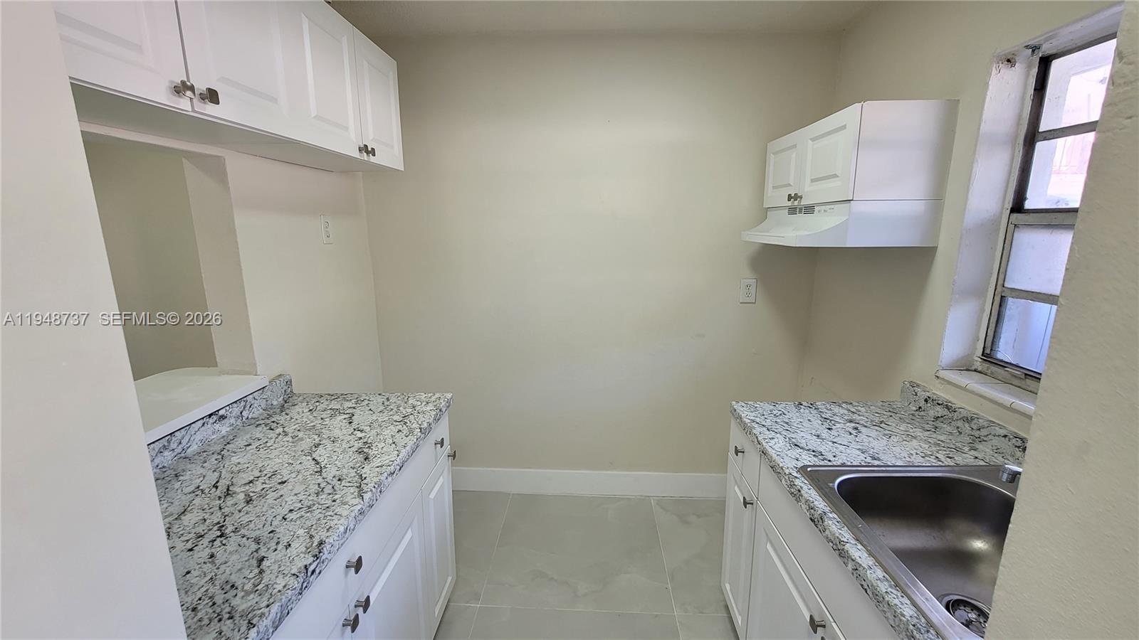 A small kitchen features white cabinets, granite countertops, and a stainless steel sink — 13240 Port Said Rd # 19, Opa-Locka FL 33054, OPA-LOCKA, FL
