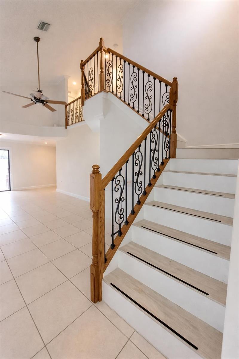 A staircase with white risers and light wood treads features a wooden railing with decorative metal balusters — 9856 Watermill Circle # C, Boynton Beach FL 33437, BOYNTON BEACH, FL