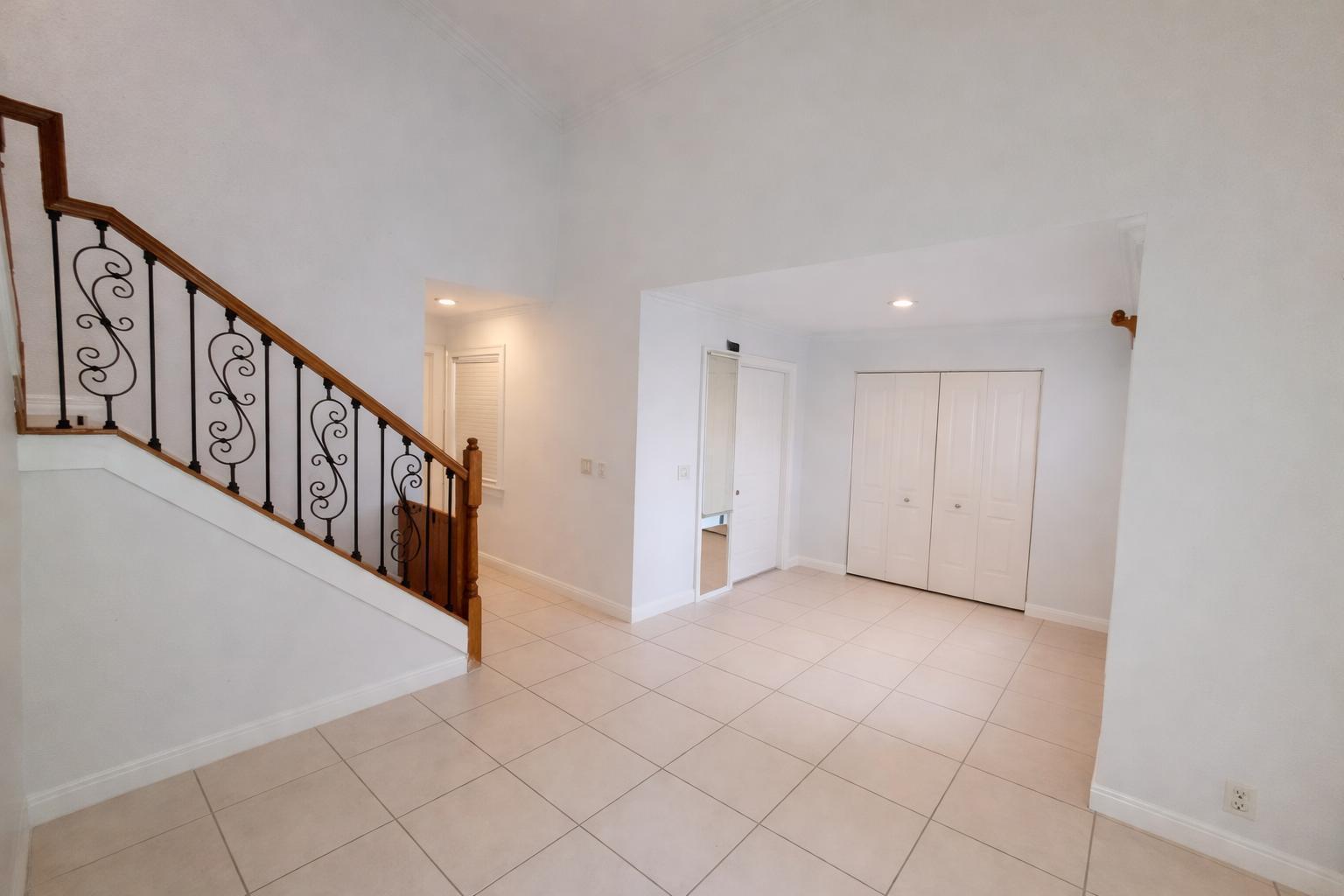 An entryway with light tile flooring, a staircase with decorative iron railings, and white closets — 9856 Watermill Circle # C, Boynton Beach FL 33437, BOYNTON BEACH, FL