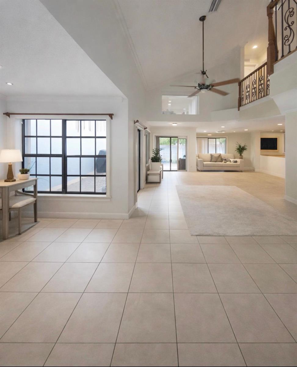 An open-concept living area features light tile flooring, a vaulted ceiling, and a wooden staircase — 9856 Watermill Circle # C, Boynton Beach FL 33437, BOYNTON BEACH, FL