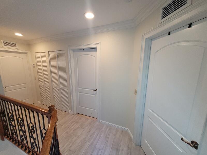A hallway features light wood-look tile flooring, white paneled doors, and a wooden stair railing — 9856 Watermill Circle # C, Boynton Beach FL 33437, BOYNTON BEACH, FL