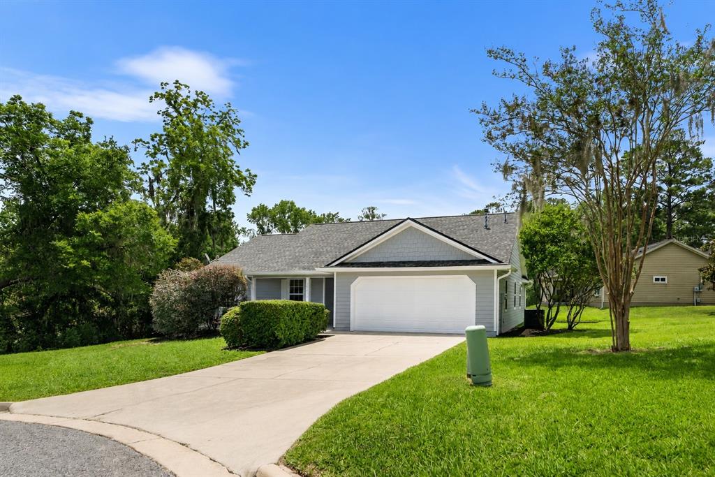 A single-story house with gray siding, a white garage door, and a concrete driveway — 14611 NW 150TH LANE, ALACHUA, FL