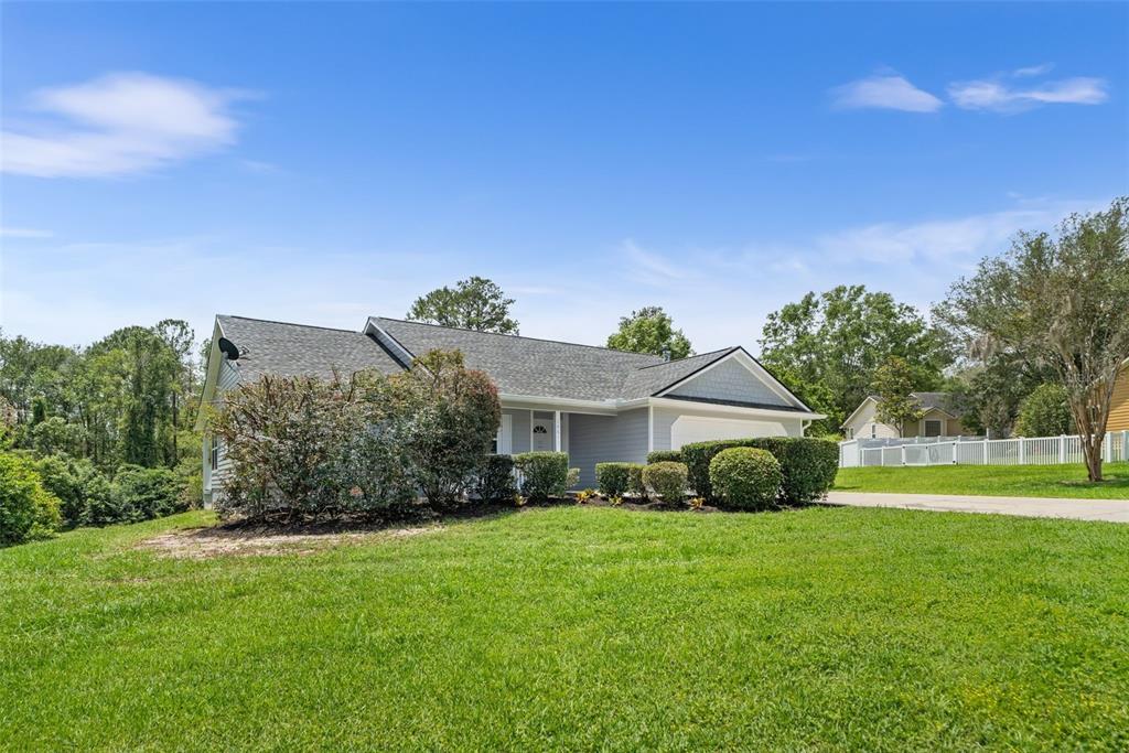 A single-story house with gray siding and a shingled roof sits on a grassy lot — 14611 NW 150TH LANE, ALACHUA, FL