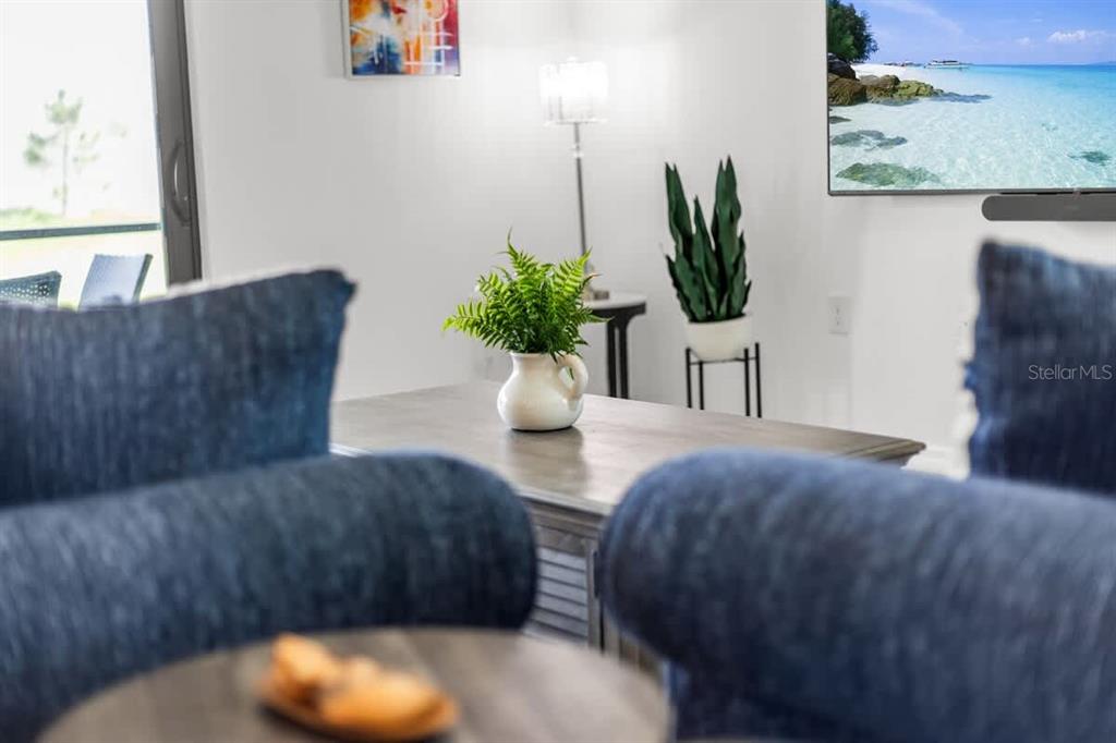 A living room features a coffee table with a plant, a television, and blue furniture — 1638 SADDLEWOOD CIRCLE, PORT CHARLOTTE, FL