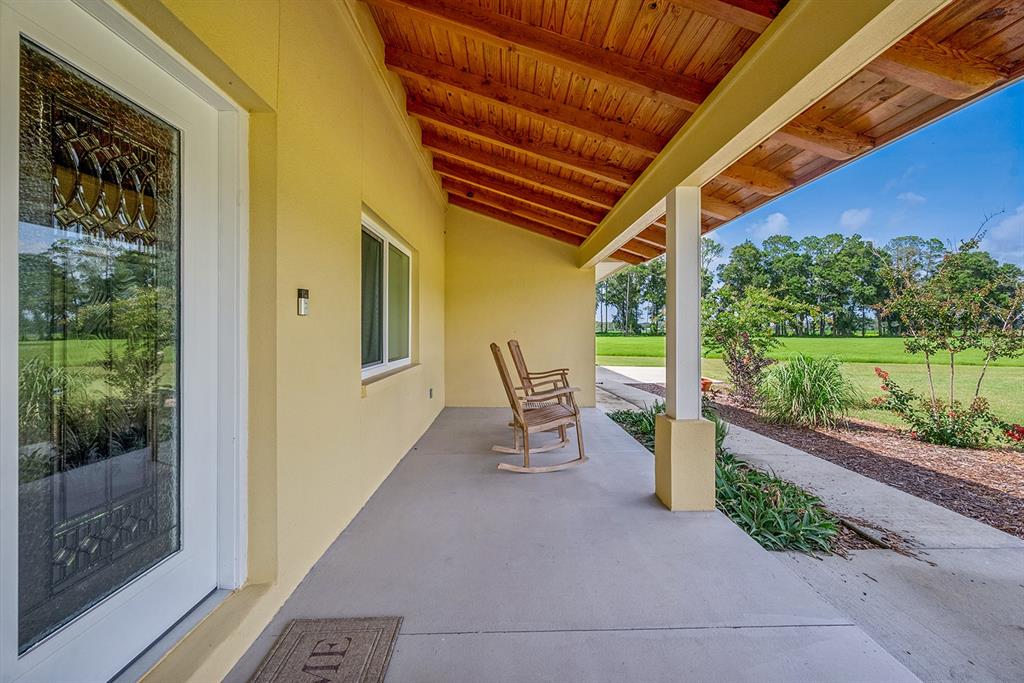 A covered porch with a concrete floor, wooden ceiling, and two wooden rocking chairs — 4261 NW 57TH COURT, CHIEFLAND, FL