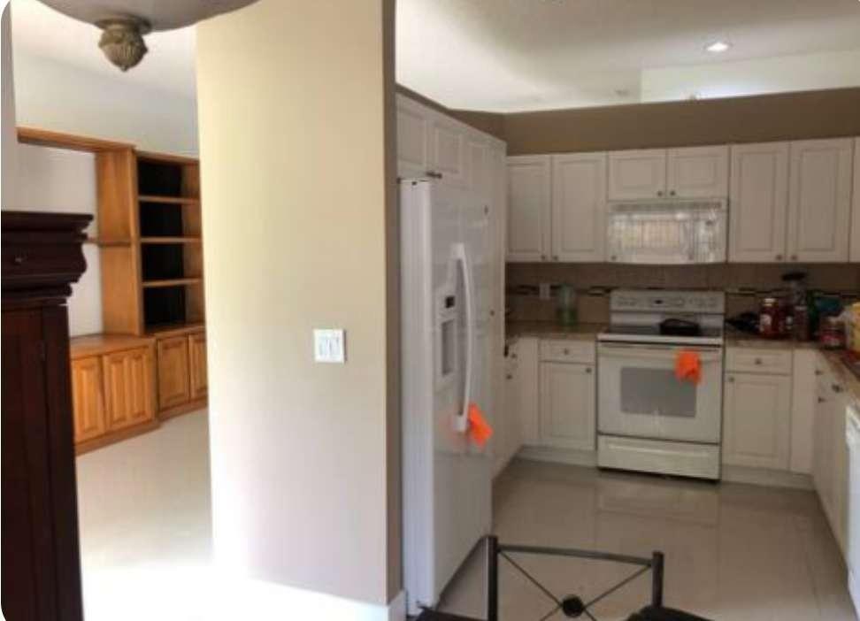A kitchen with white cabinets and appliances adjacent to a room with wooden built-in shelves — 862 Vista Meadows Drive, Weston FL 33327, WESTON, FL