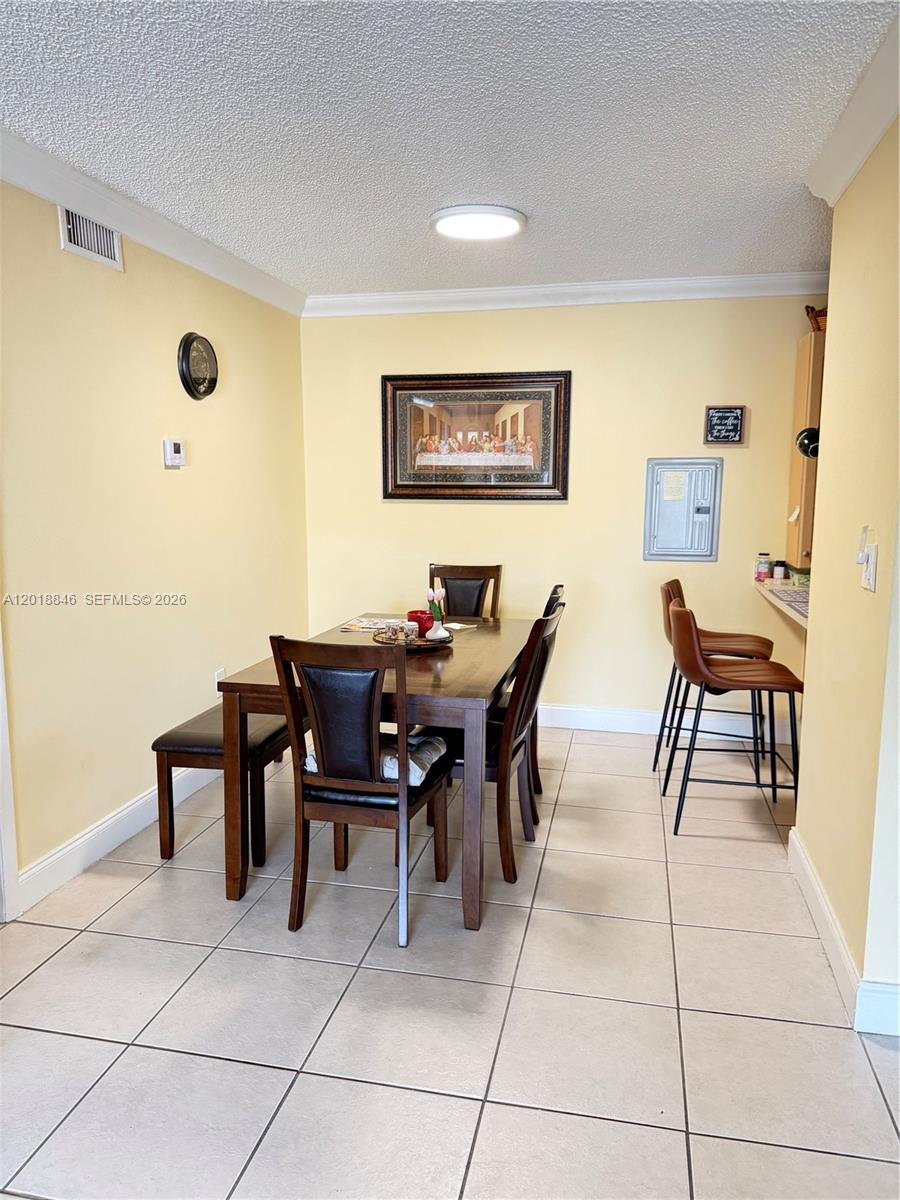 A dining area features a wooden table with chairs and a bench on tiled floors — 13781 SW 66th St # 231B, Miami FL 33183, MIAMI, FL