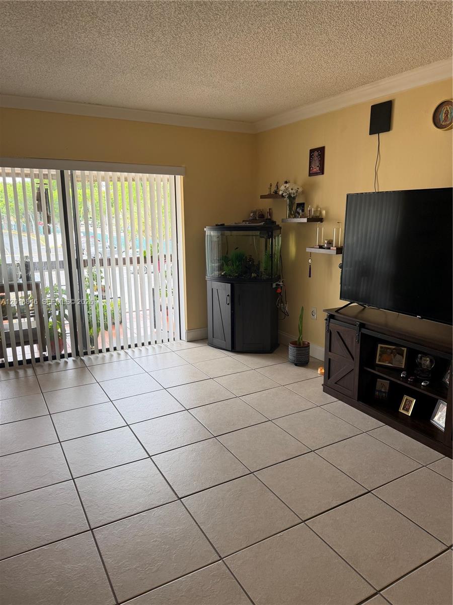 A living room with tile flooring, a television console, a fish tank, and sliding glass doors — 13781 SW 66th St # 231B, Miami FL 33183, MIAMI, FL