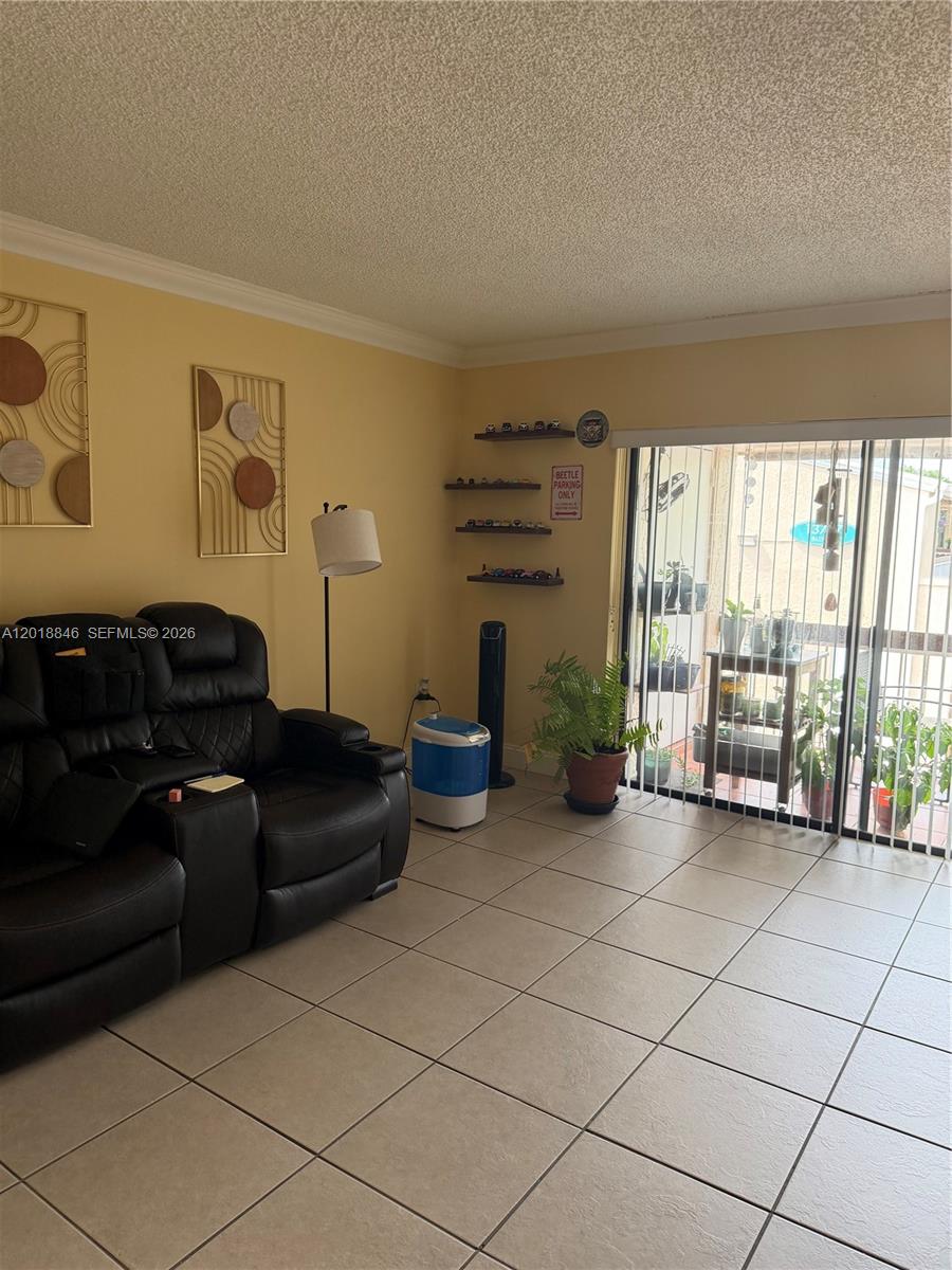 A living room features a black leather recliner, tile flooring, wall art, and a sliding door — 13781 SW 66th St # 231B, Miami FL 33183, MIAMI, FL