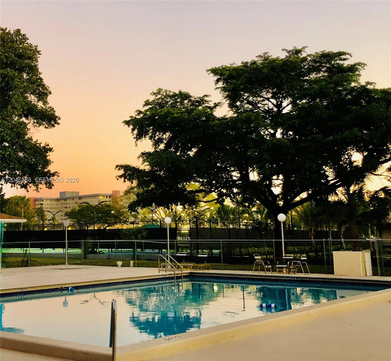 A swimming pool sits in front of a large tree and a tennis court — 919 Hillcrest Dr # 302, Hollywood FL 33021, HOLLYWOOD, FL