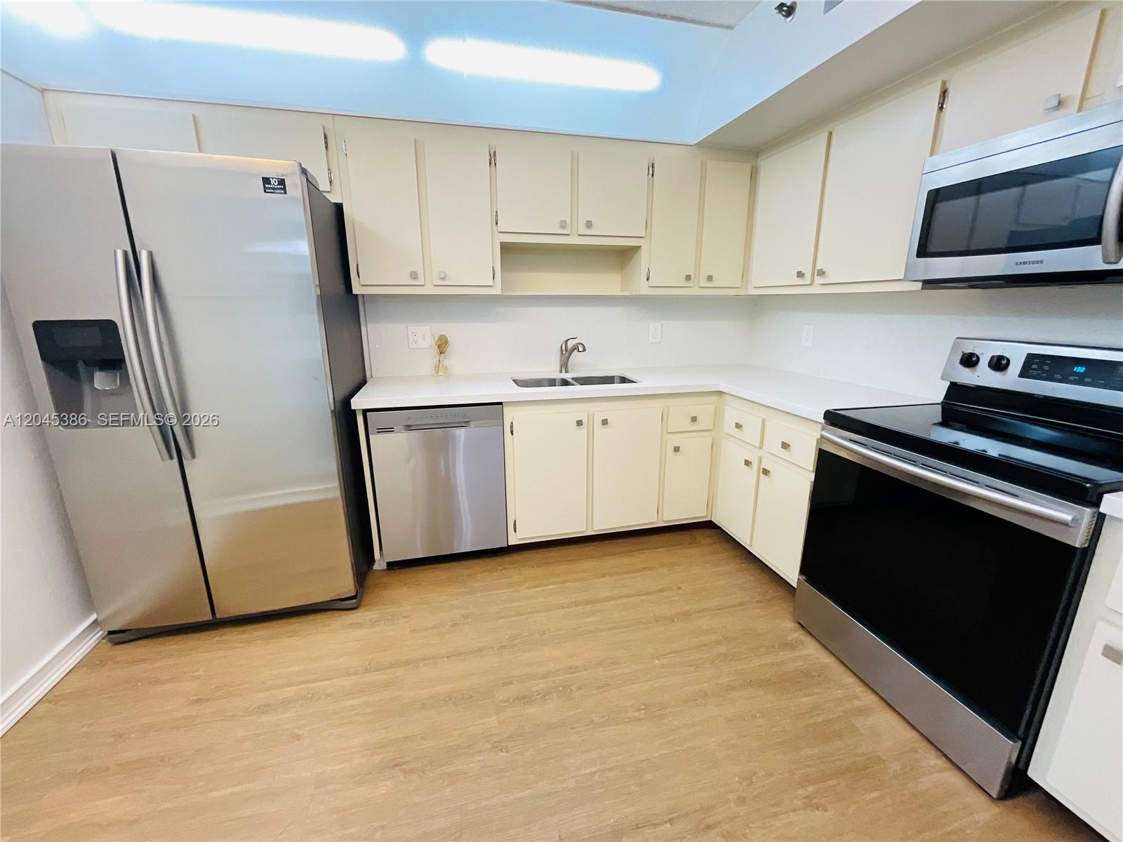 A kitchen features stainless steel appliances, light-colored cabinets, and wood-look flooring — 919 Hillcrest Dr # 302, Hollywood FL 33021, HOLLYWOOD, FL