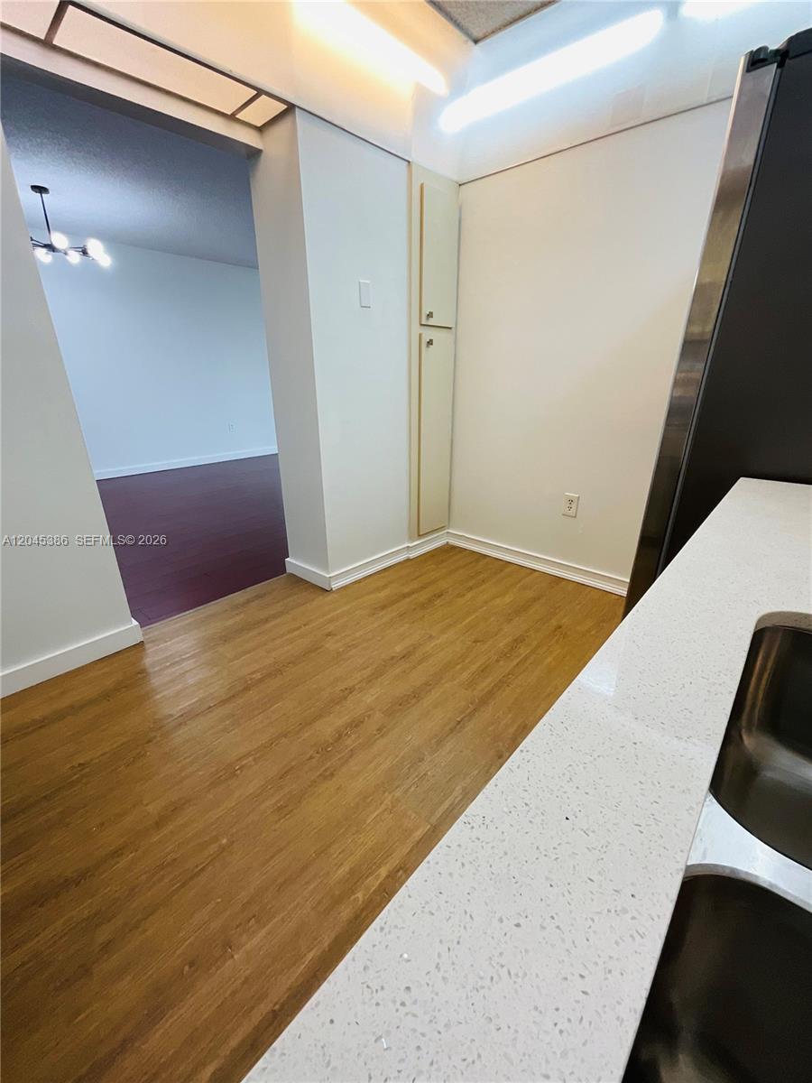 A kitchen area features light wood-look flooring, white walls, and a tall pantry cabinet — 919 Hillcrest Dr # 302, Hollywood FL 33021, HOLLYWOOD, FL