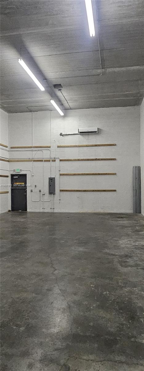 An empty industrial warehouse space features concrete floors, white walls, and overhead fluorescent lighting — 15075 SW 137th St # 14, Miami FL 33196, MIAMI, FL