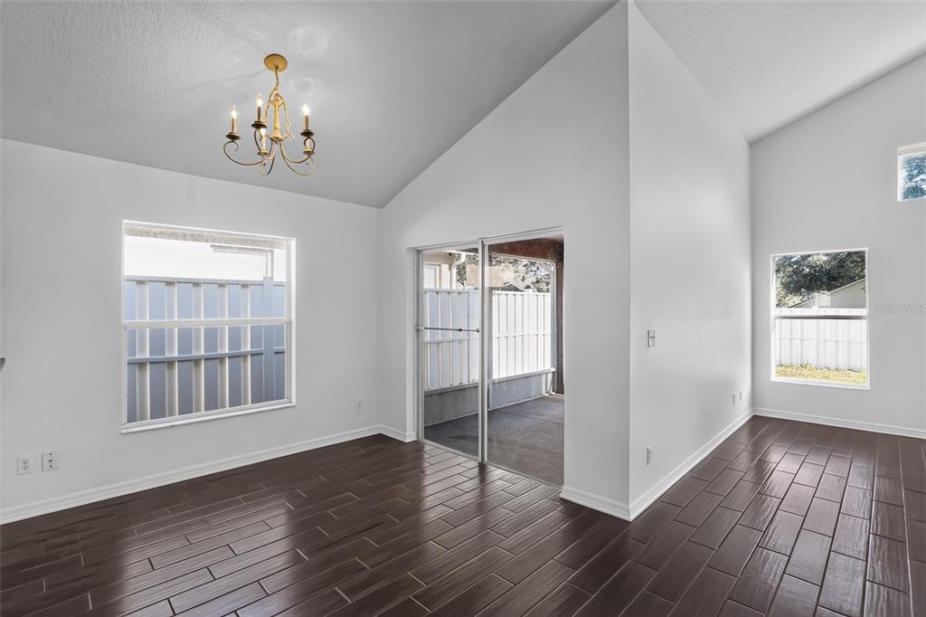 A dining area with dark wood-look tile flooring, a vaulted ceiling, and sliding glass doors — 2079 NEWTOWN ROAD, GROVELAND, FL