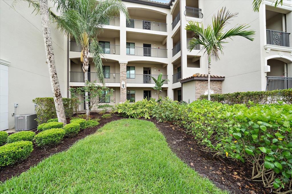 A multi-story apartment building exterior features balconies, palm trees, and landscaped garden beds — 16814 VARDON TERRACE UNIT 106, BRADENTON, FL