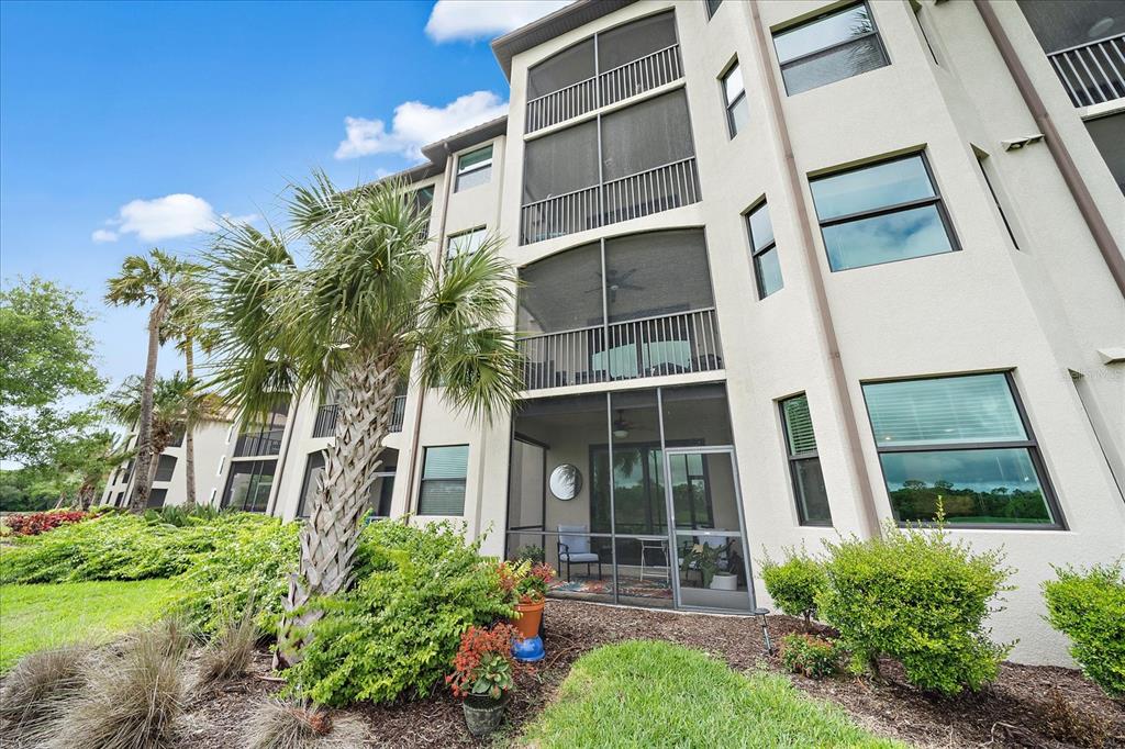 A multi-story apartment building features screened-in balconies and a landscaped lawn with palm trees — 16814 VARDON TERRACE UNIT 106, BRADENTON, FL