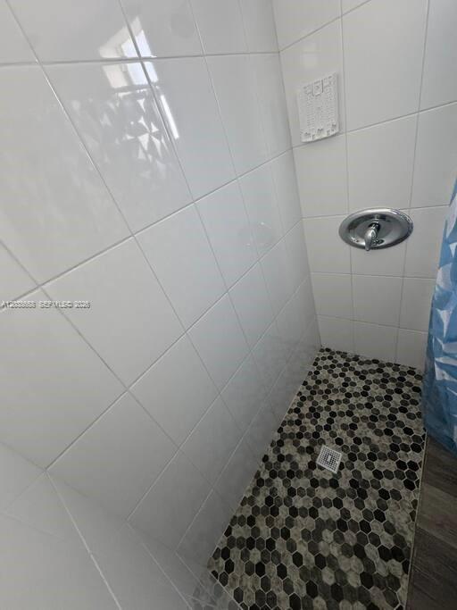 A walk-in shower features white wall tiles, a patterned hexagonal floor, and chrome fixtures — 7638 N Miami Ave # 1, Miami FL 33150, MIAMI, FL
