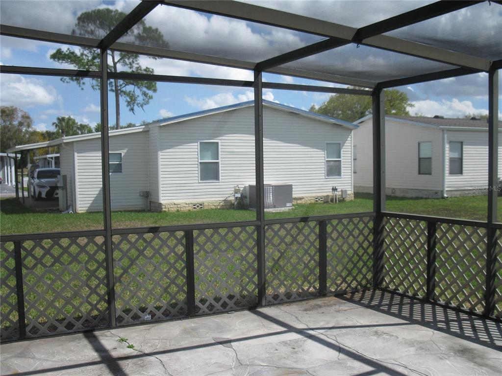 A screened-in patio with a concrete floor overlooks a neighboring house and yard — 356 MELBOURN DRIVE, HAINES CITY, FL