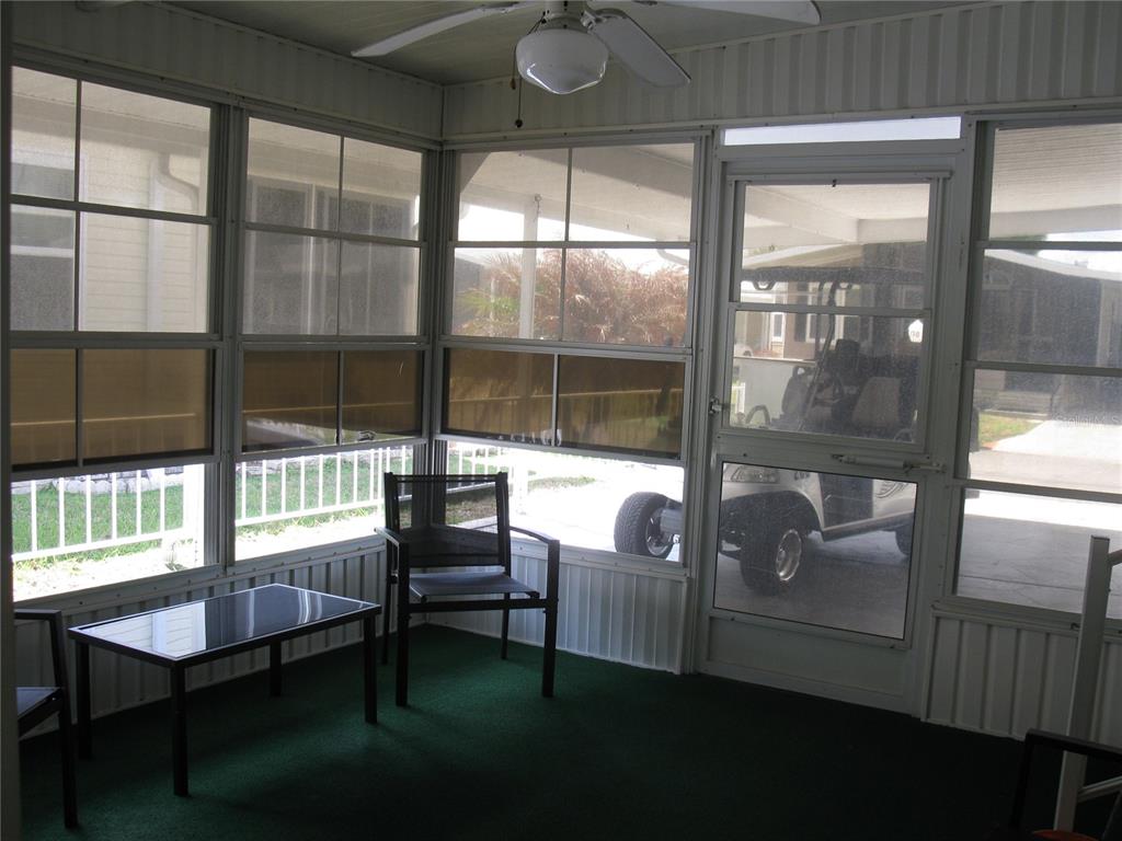 A screened-in porch features green carpeting, a small table, a chair, and a golf cart — 356 MELBOURN DRIVE, HAINES CITY, FL