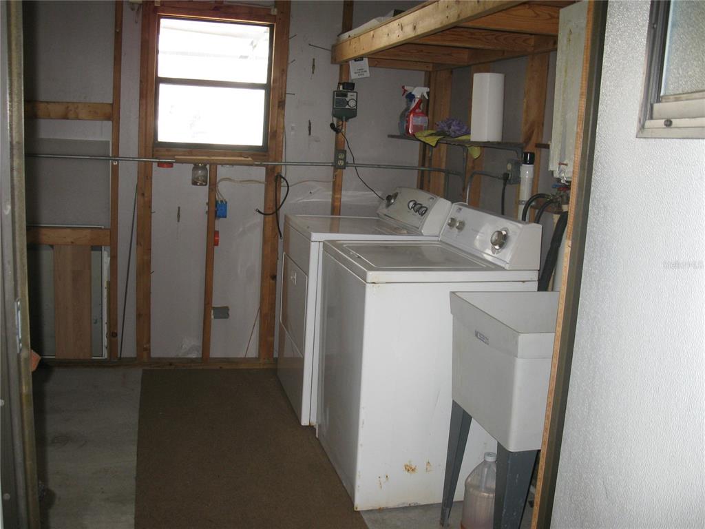 A laundry room features a washer, dryer, utility sink, and unfinished wall framing — 356 MELBOURN DRIVE, HAINES CITY, FL