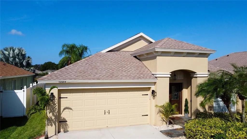 A single-story house with a tan stucco exterior, a two-car garage, and a tiled roof — 12213 RAVENS NEST PLACE, RIVERVIEW, FL