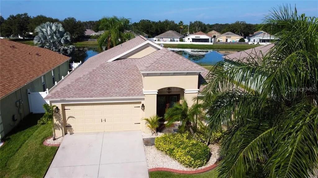 An aerial view of a single-story suburban house with a tan exterior and pond — 12213 RAVENS NEST PLACE, RIVERVIEW, FL