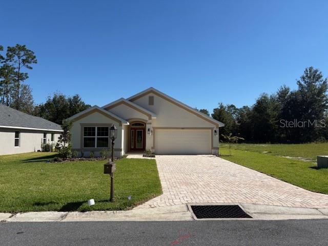 A single-story house with a beige stucco exterior, a paved driveway, and a two-car garage — 7625 SW 180TH CIRCLE, DUNNELLON, FL