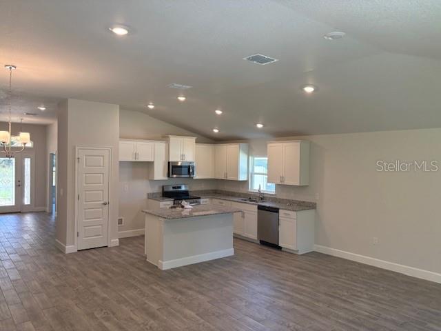 A kitchen features white cabinets, granite countertops, a center island, and wood-look tile flooring — 7625 SW 180TH CIRCLE, DUNNELLON, FL