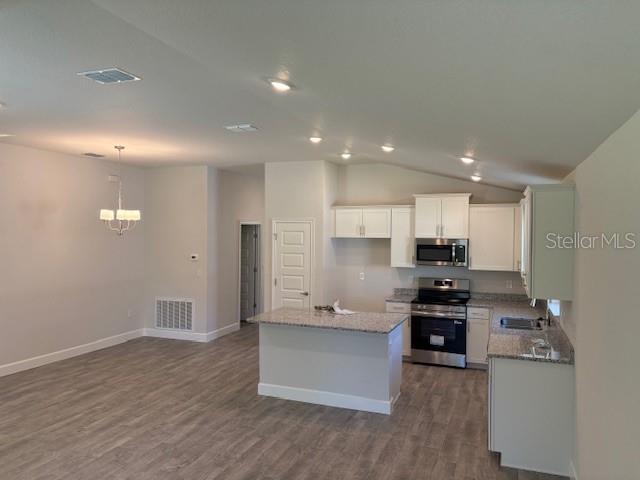 An open-concept kitchen and dining area features light-colored cabinetry, granite countertops, and wood-look flooring — 7625 SW 180TH CIRCLE, DUNNELLON, FL