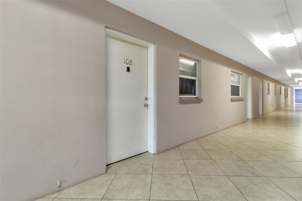 A long, tiled hallway features a white door labeled 108 and several windows — 3100 HARBOR BOULEVARD UNIT 108, PORT CHARLOTTE, FL