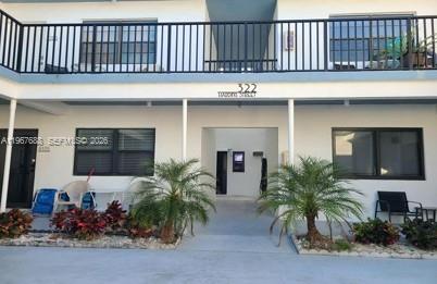 The exterior of a two-story apartment building features a balcony, palm trees, and windows — 322 Harding St # B202, Hollywood FL 33019, HOLLYWOOD, FL