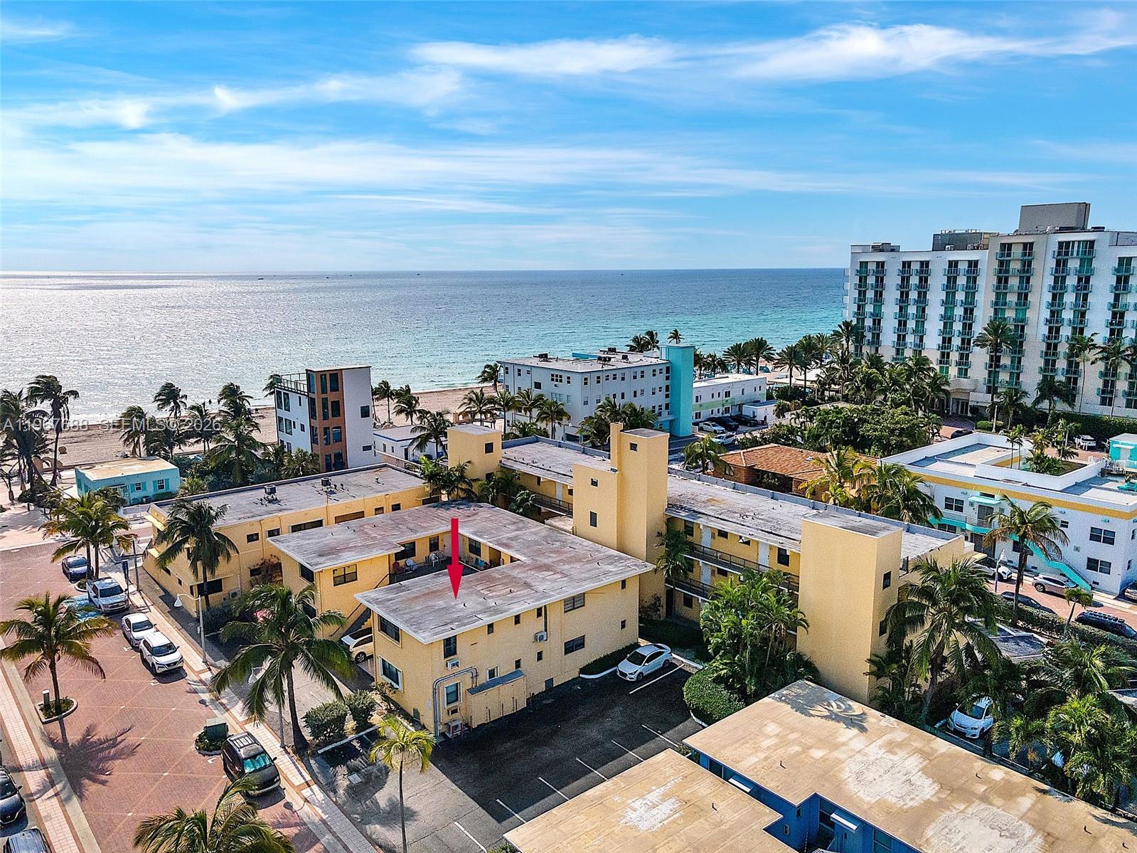 An aerial view shows a yellow multi-story apartment complex near the ocean — 322 Harding St # B202, Hollywood FL 33019, HOLLYWOOD, FL