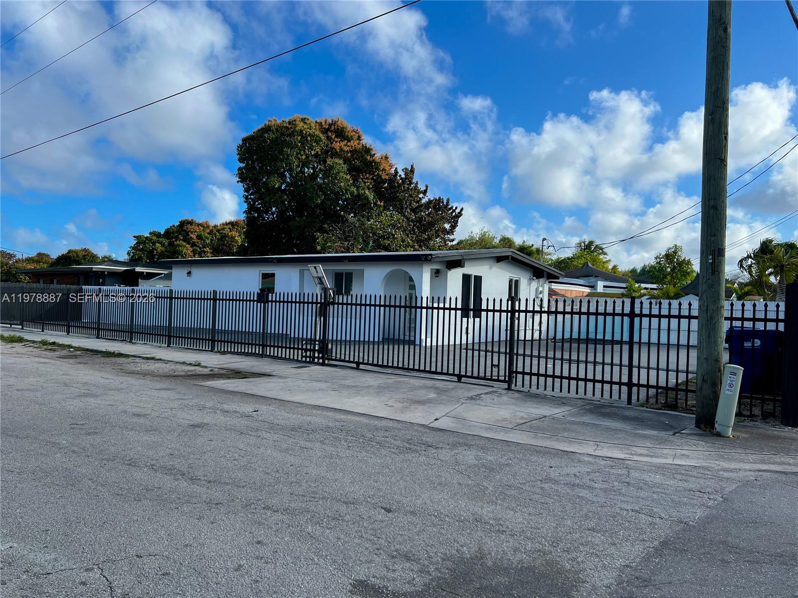 A white single-story house is enclosed by a tall black metal fence — 10090 W Fern St, Miami FL 33157, MIAMI, FL