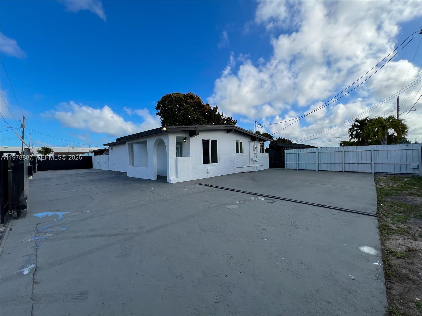 A white single-story house features a large concrete driveway and a white privacy fence — 10090 W Fern St, Miami FL 33157, MIAMI, FL