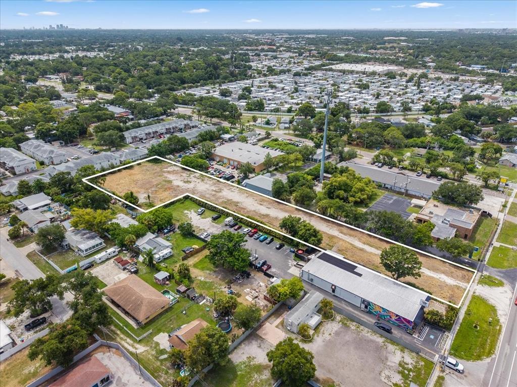 An aerial view shows a vacant, rectangular lot outlined in white next to commercial buildings — 4685 PARK STREET N, ST PETERSBURG, FL