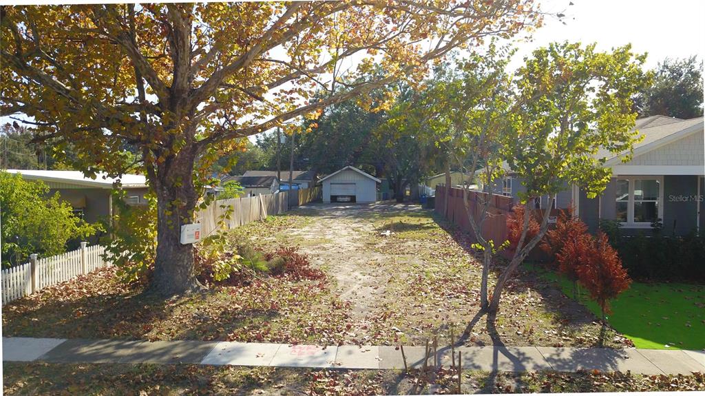 A vacant, leaf-covered lot sits between two houses with a detached garage in the back — 730 50TH AVENUE N, ST PETERSBURG, FL