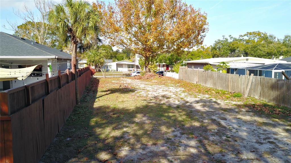 A narrow, sandy residential lot is enclosed by wooden fences with a large tree — 730 50TH AVENUE N, ST PETERSBURG, FL