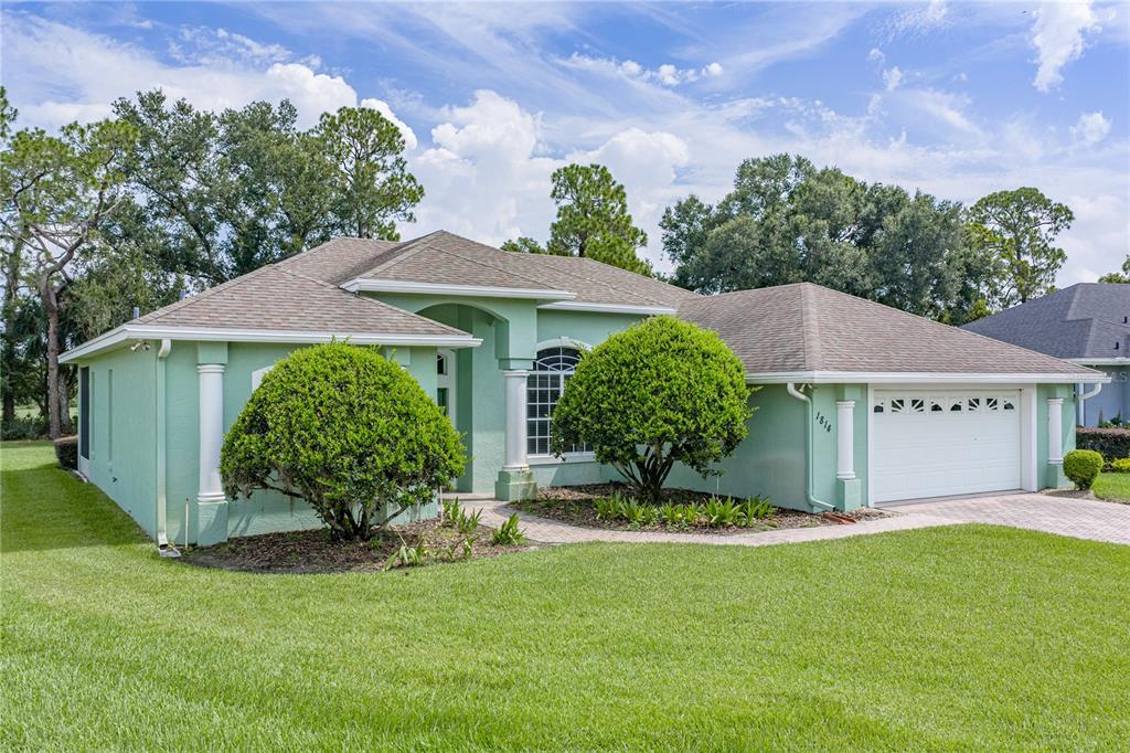 A light green single-story house with a two-car garage and a paved walkway — 1814 SANDHILL LANE, WINTER HAVEN, FL