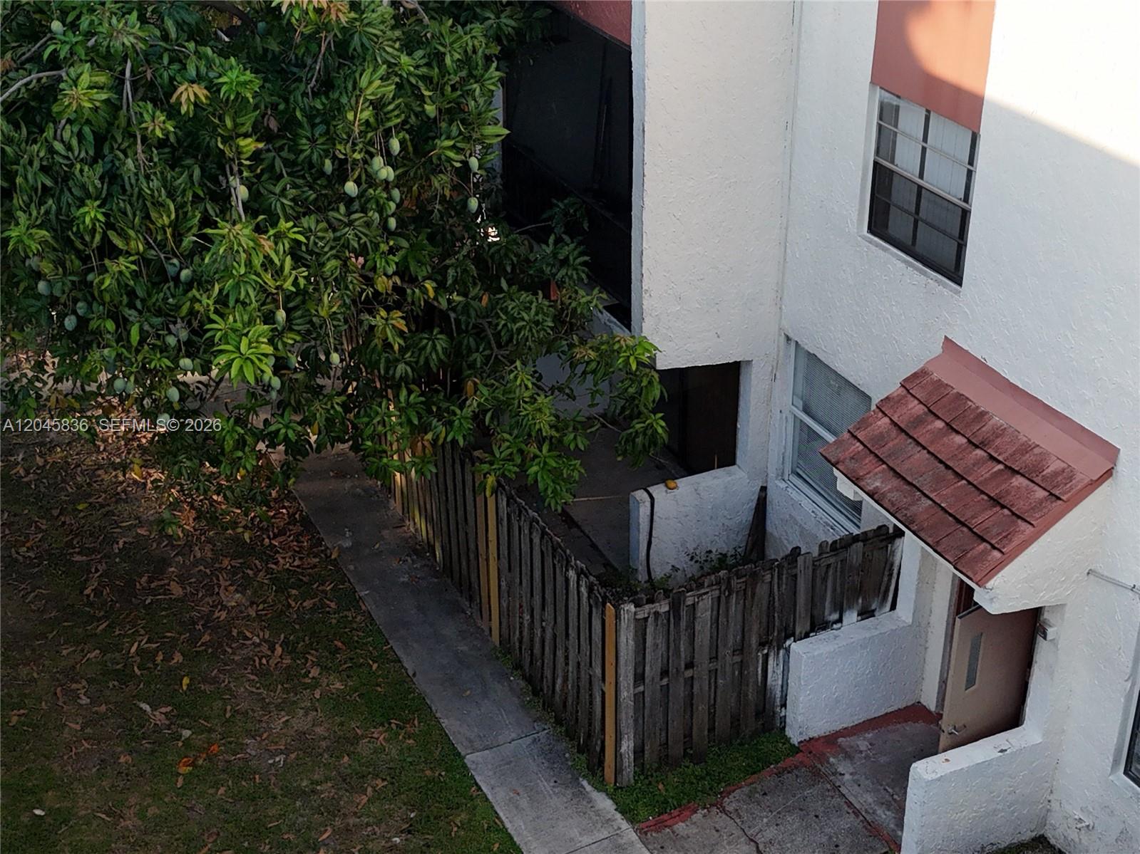 An elevated view shows a residential building exterior with a fenced patio and mango tree — 1750 NW 55th Ave # 103, Lauderhill FL 33313, LAUDERHILL, FL