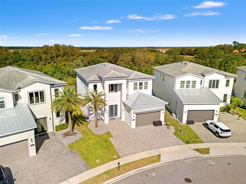 An aerial view shows three modern two-story houses with paved driveways and palm trees — 2021 OAK CREEK LOOP, DAVENPORT, FL