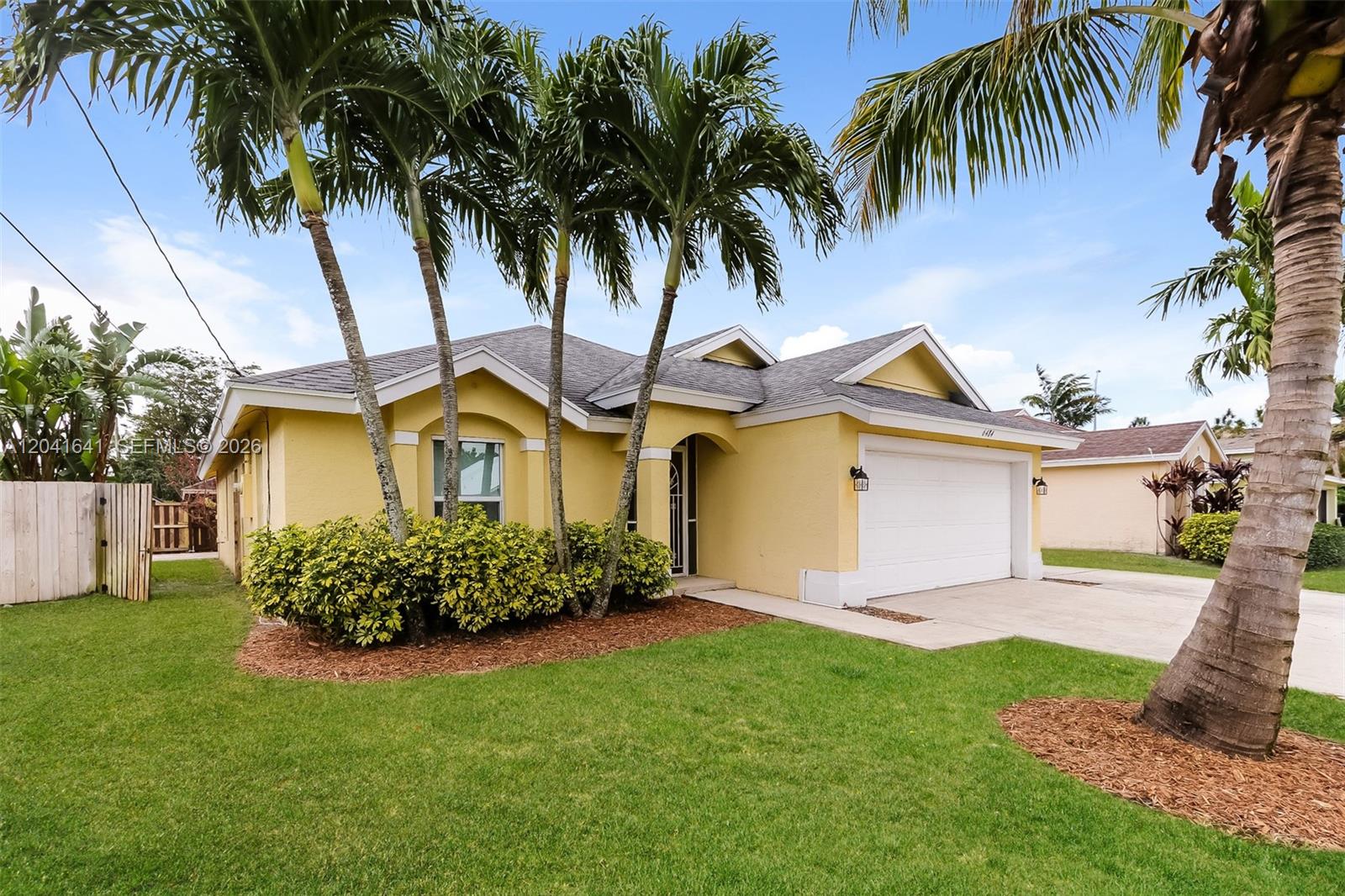 A yellow single-story house with a white garage door and palm trees in the front yard — 6484 Robinson St, Jupiter FL 33458, JUPITER, FL
