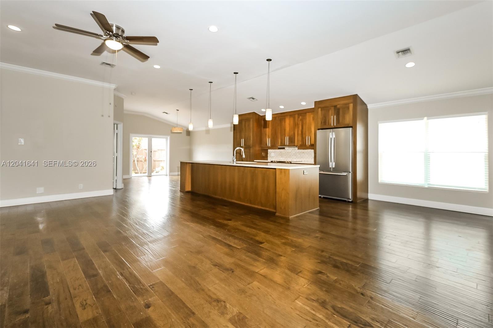 A kitchen with wood cabinets, a large island, and hardwood floors in an open space — 6484 Robinson St, Jupiter FL 33458, JUPITER, FL