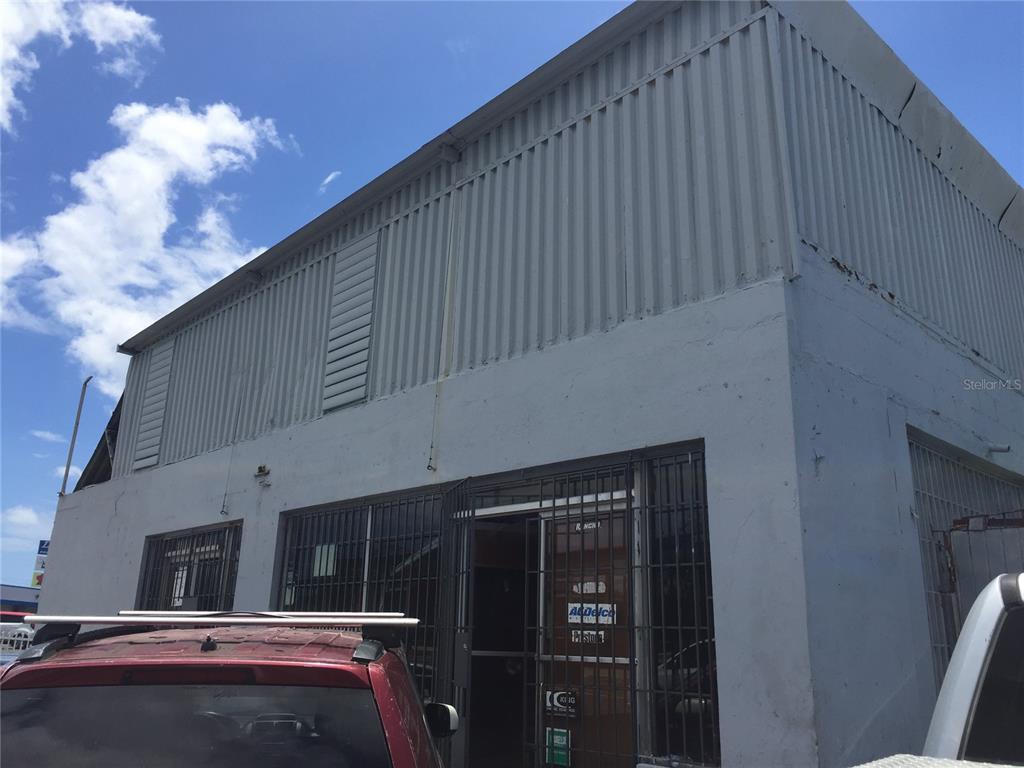 A low-angle exterior view of a commercial building with corrugated metal siding and security bars — 1710 Las Lomas Dev. JESUS T. PINERO AVE., SAN JUAN, PR
